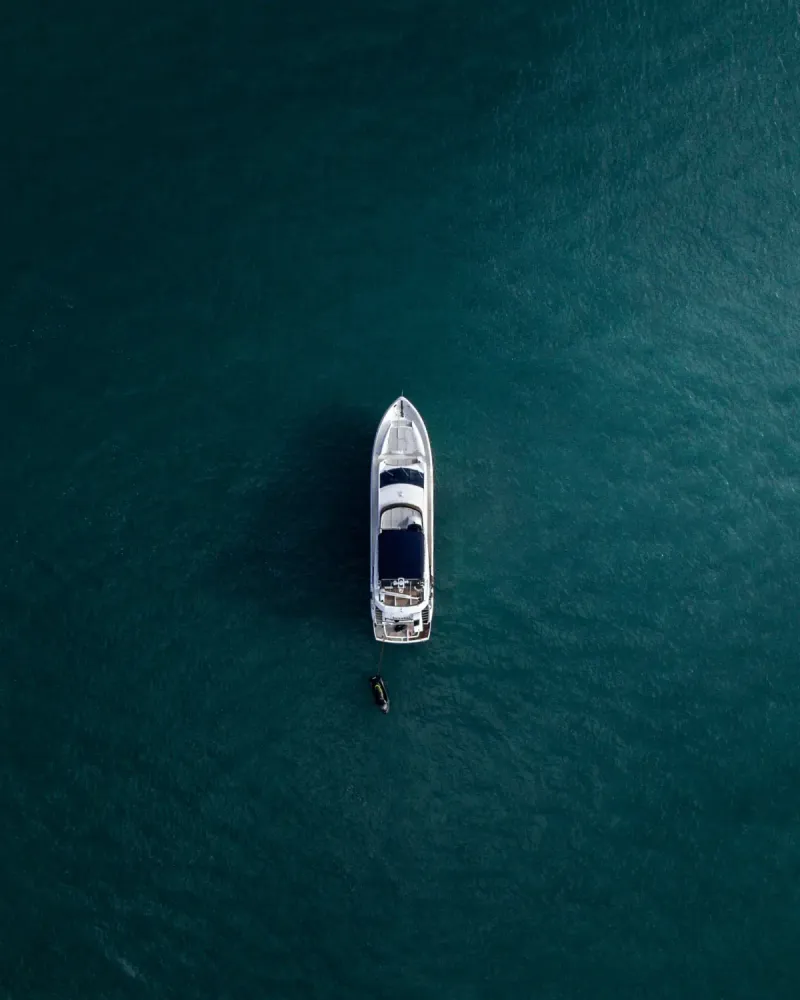 A boat at anchor on deep water, seen from above